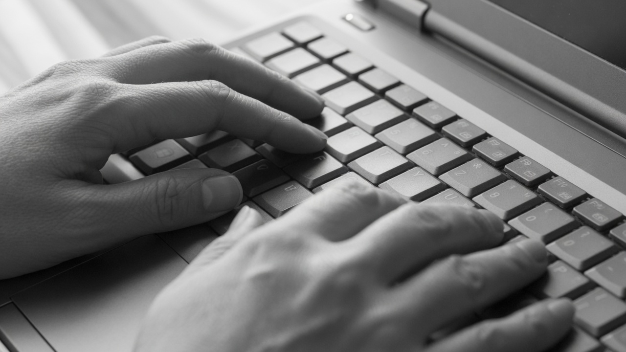 Hands resting on a laptop keyboard
